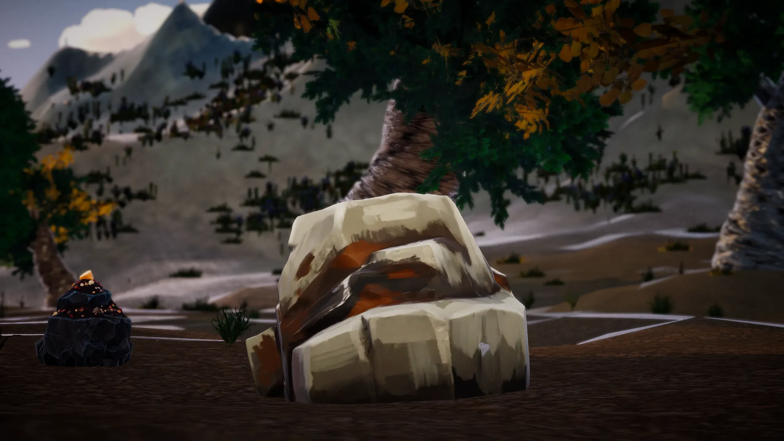 A large boulder in a rocky clearing below a tree and a snowy mountain.
